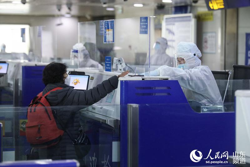 青島機場出入境邊防檢查站執勤八隊民警鄒琳為旅客遞還出入境証件。（攝影 解豪）