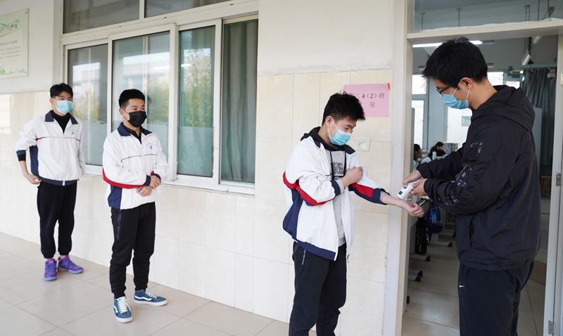 山東省鄒平市第一中學高三4（2）班學生在教室門口測量體溫，原先的班級分成了2個小班。攝影：董乃德