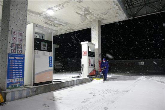 煙台蓬萊23站員工雪夜清掃積雪。 （朱冰攝）