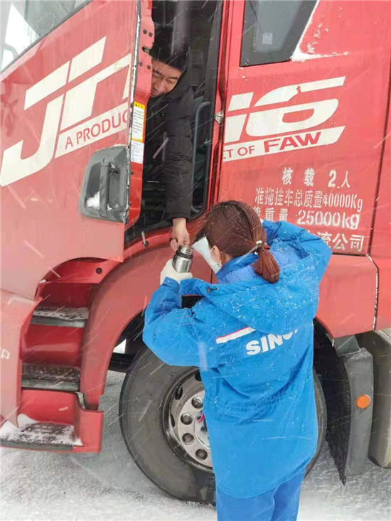 員工冒雪為貨車司機送熱水。（張利利攝）