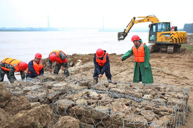 10月8日，駐守在黃河下游最窄艾山卡口處的基層防汛工作人員，為做好工程防護排壘鉛絲籠石。 張濤攝