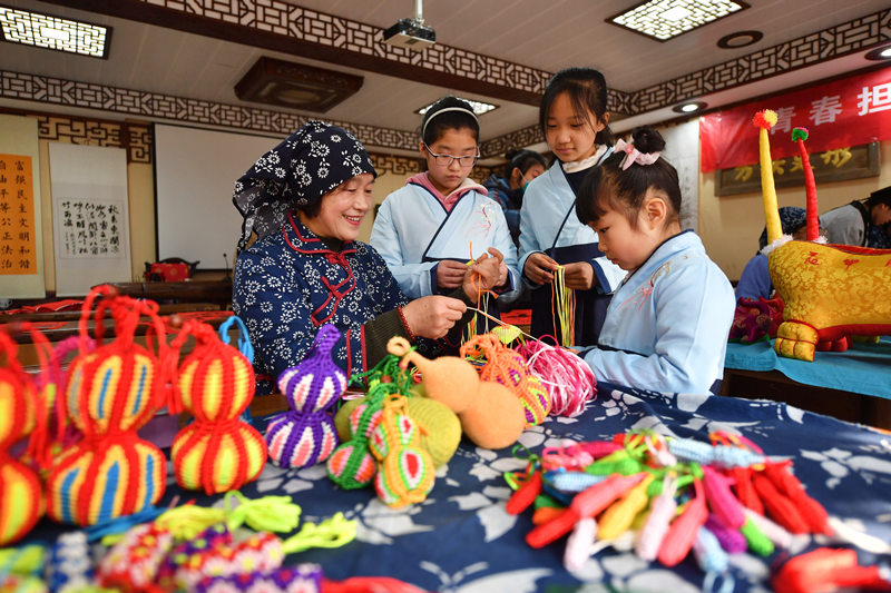 2022年春節臨近，在山東省青島市城陽區紅島街道韓家民俗村，民間藝人向孩子們傳授手編葫蘆技巧。 王海濱攝