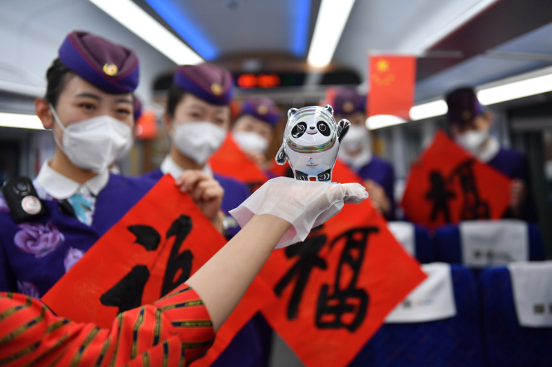 2022年1月25日，在山东青岛开往龙口（济南～菏泽）的C664次绿巨人复兴号首趟列车上，乘务人员展示为旅客准备的冬奥会吉祥物“冰墩墩”。 王海滨摄