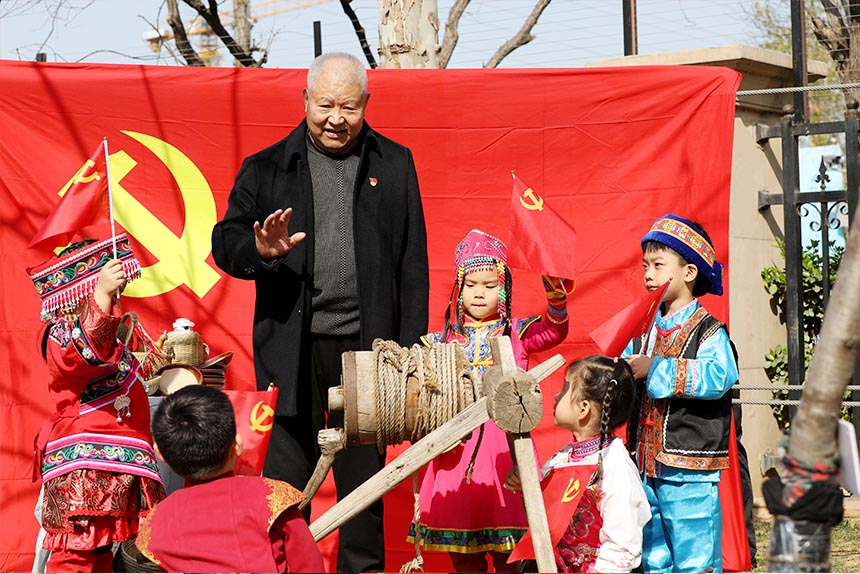 老黨員韓奎文在轆轤井邊，為孩子講述《吃水不忘挖井人》的紅色革命故事。劉祺攝