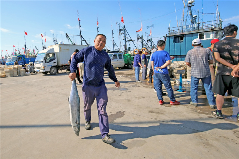 一位市民正在日照中心渔港港码头抢购今秋最新鲜的鱼货海鲜。薄林 摄
