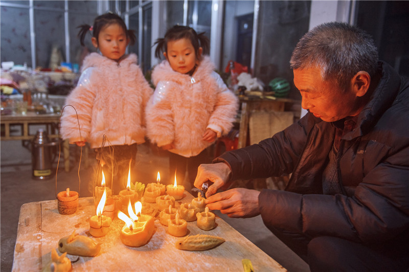 老人为孩子点亮面灯。陈光金 摄