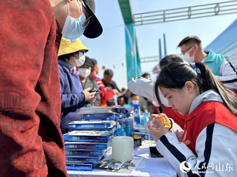 濟南傳媒學校“心燭”志願隊的同學們為市民提供免費貼手機膜的暖心服務。人民網 喬姝攝