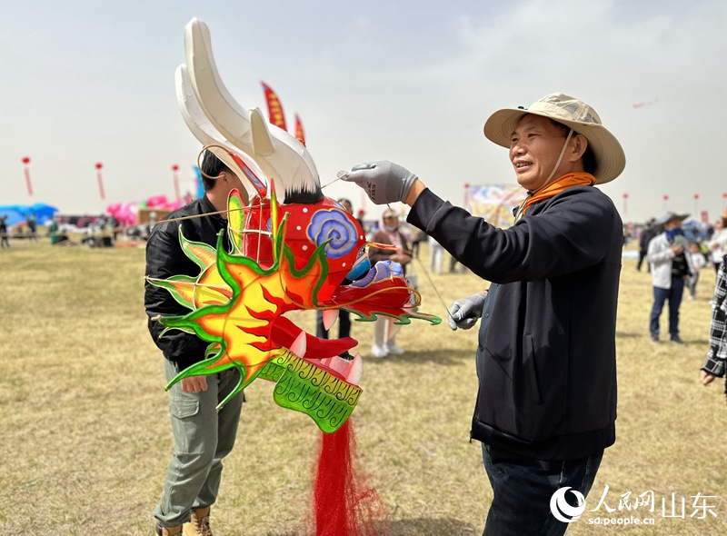 風箏比賽參賽者正在整理龍頭蜈蚣風箏，為放飛做准備。人民網 喬姝攝