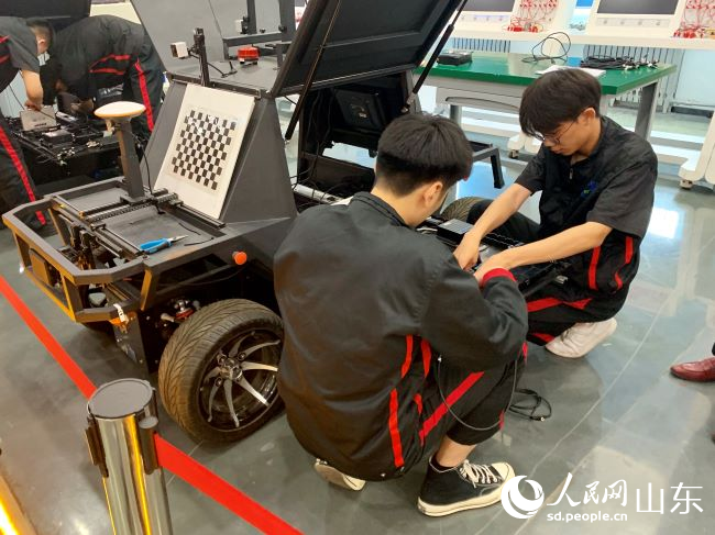 汽车学院内，两名学生正在安装智能网联小车 人民网 逄鑫珊摄