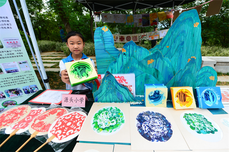 一名源頭小學的學生在展示生態剪紙作品。王海濱攝