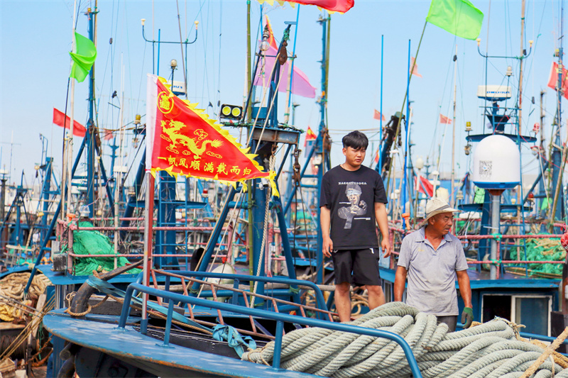 在日照黄海中心渔港内,渔民正在往船上装物资。薄林摄