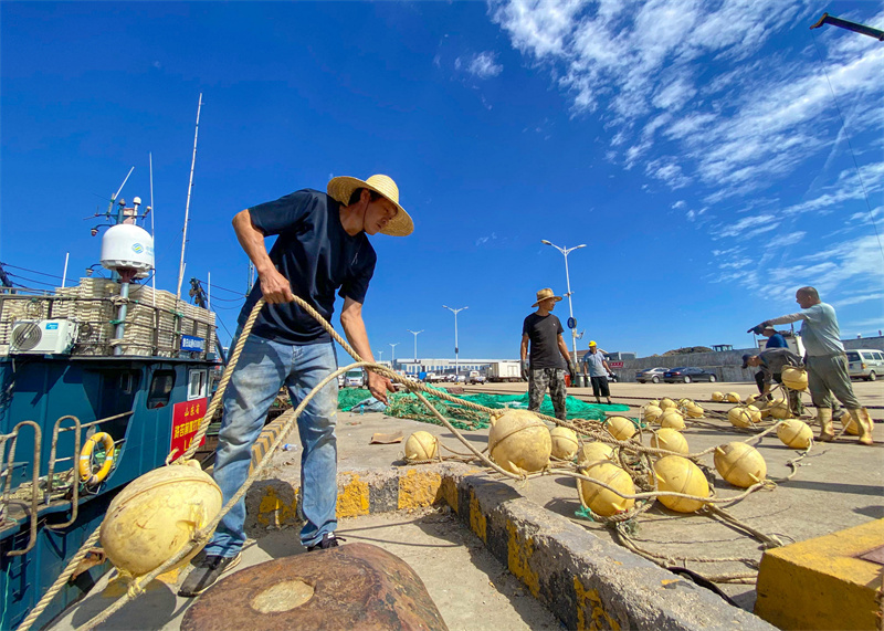 在日照黄海中心渔港内,渔民正在往船上装装渔网。薄林摄