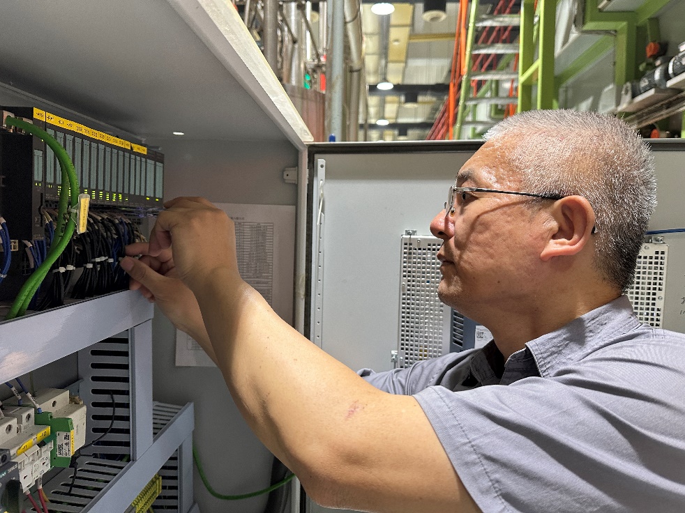 圖為電氣維修工劉偉達檢查梗加料系統預填充無流量，核對管路氣動閥開關到位信號是否進入PLC輸入模塊 拍攝者：徐勝杰
