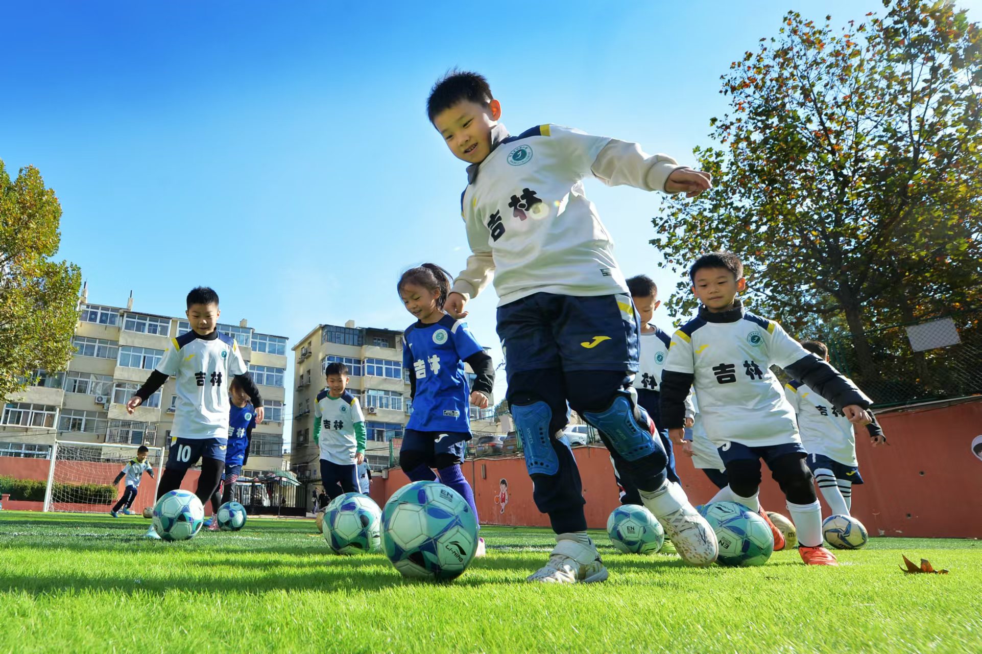 2024年11月18日，在山东青岛吉林路小学开展的足球冬训活动上，孩子们在绿茵场上进行带球训练。