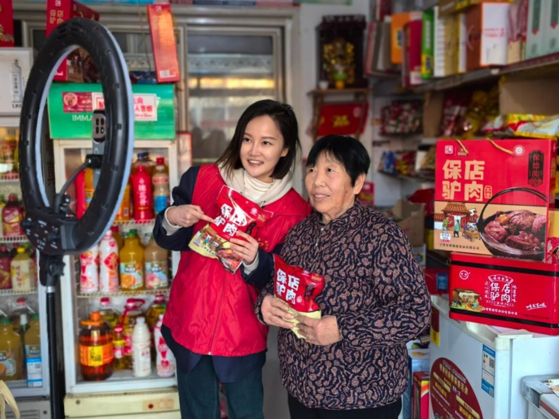 图为青年志愿者协助村民进行特色产品直播带货。