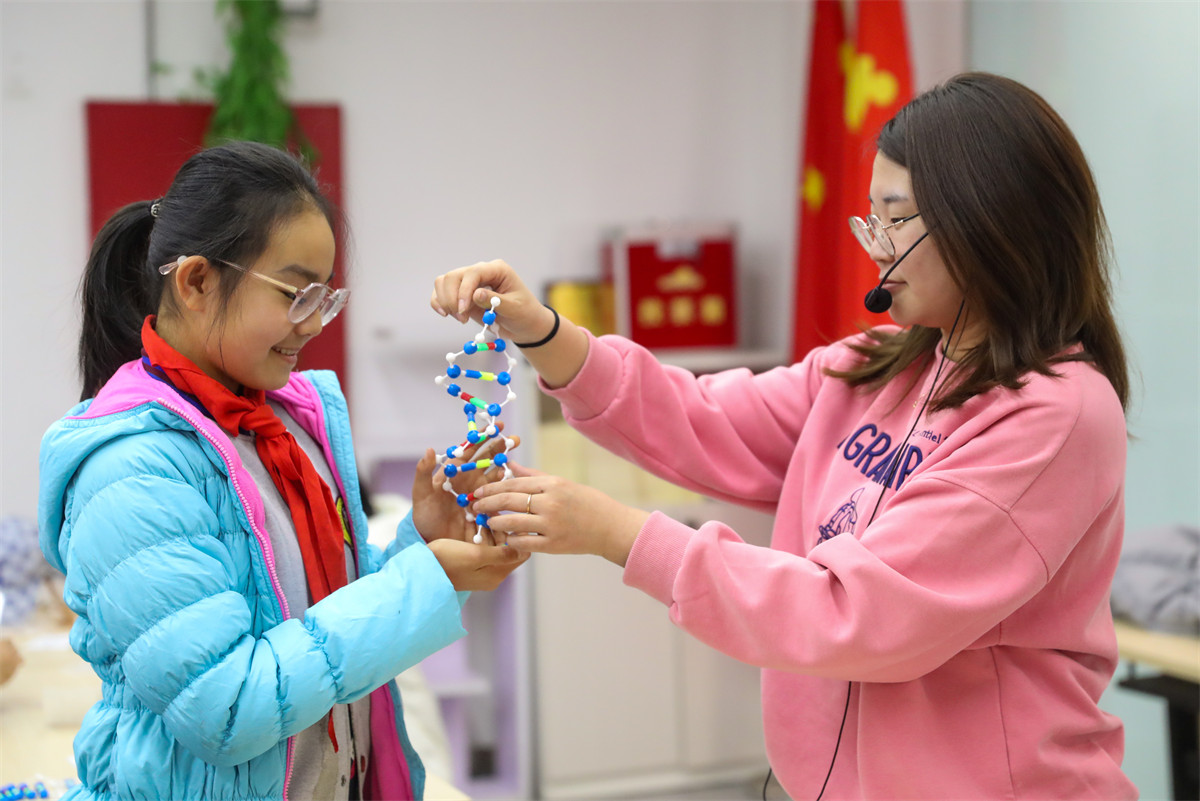 2月10日，在青島華大基因研究院，青島大學路小學六年級四班的同學在給科研人員展示剛剛拼接好的DNA模型。（張進剛攝）