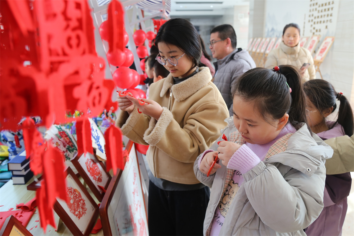 2月11日，在山东省滨州市沾化区图书馆内，小朋友们跟着非遗传承人学习剪纸。