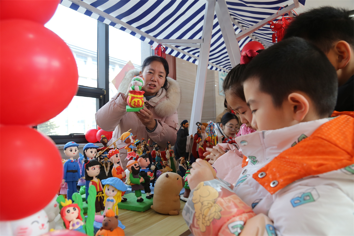 2月11日，在山东省滨州市沾化区图书馆内，小朋友们跟着非遗传承人学习制作泥塑。