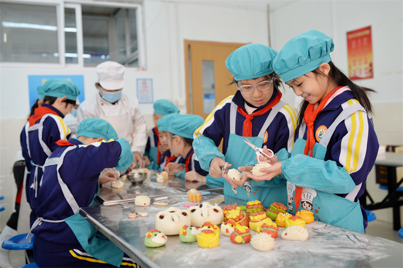 2025年3月7日，两名学生在山东青岛市北实验小学开展的妇女节“我为妈妈做花馍”主题活动上学做刺猬花馍。王海滨摄