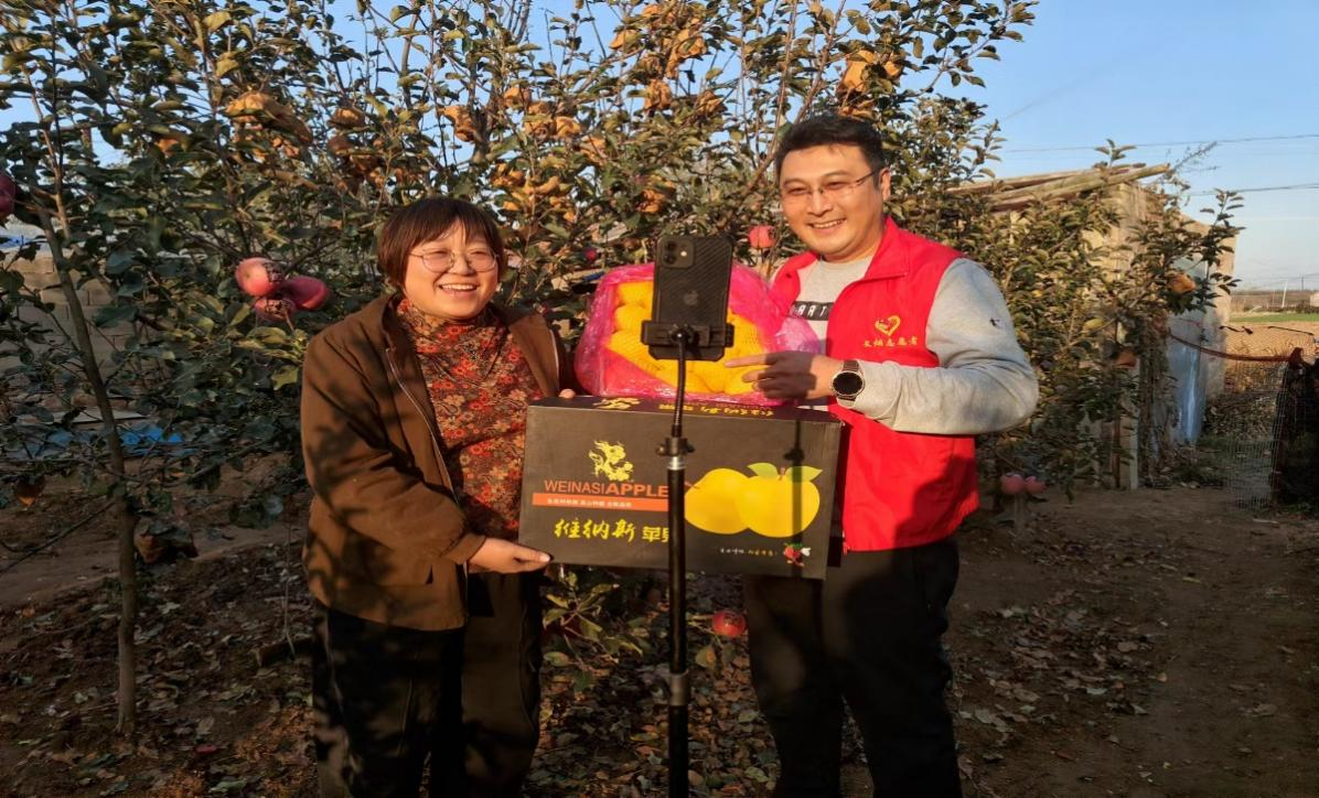 图为文登烟草志愿者在帮助村民直播带货文登苹果