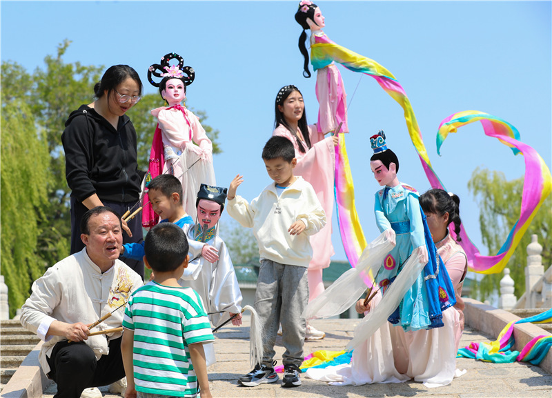 5月11日，姜玉濤和演員們在山東省萊西市月湖公園和小朋友互動。（張進剛  攝）