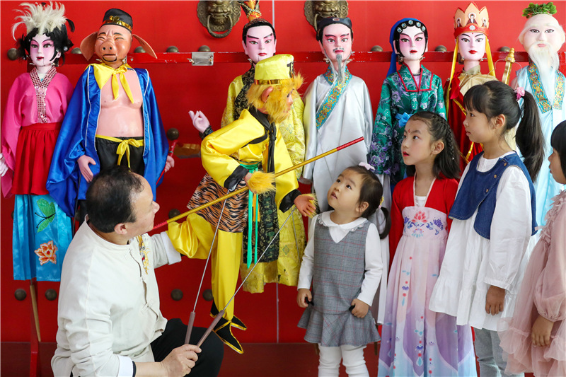 5月11日，在山東青島，姜玉濤在給小朋友演示木偶戲的表演技巧。（張進剛  攝）