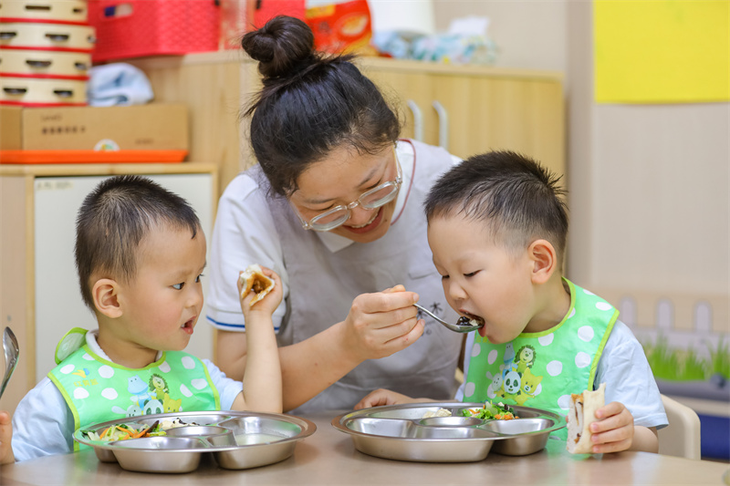 2025年5月14日，在山東省青島市李滄區職工子女愛心托育中心，老師教小朋友學吃飯。張鷹 攝 