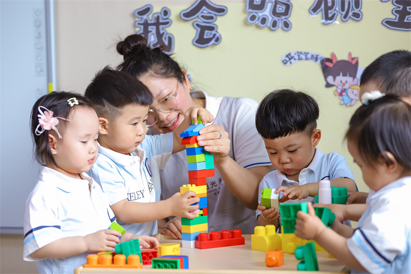 2025年5月14日，在山東省青島市李滄區職工子女愛心托育中心，小朋友在老師的陪伴下搭積木。張鷹 攝 