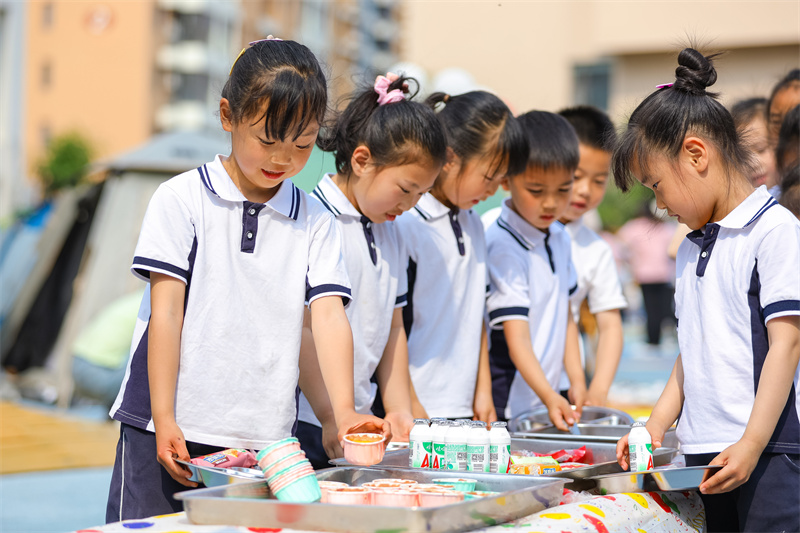 2025年5月26日，小朋友在山东省青岛市李沧区青山路幼儿园开展迎“六一”主题活动中选取美食。张鹰 摄