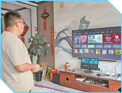 成植文调试新购入的智能电视。图为李玉杰摄（人民视觉）