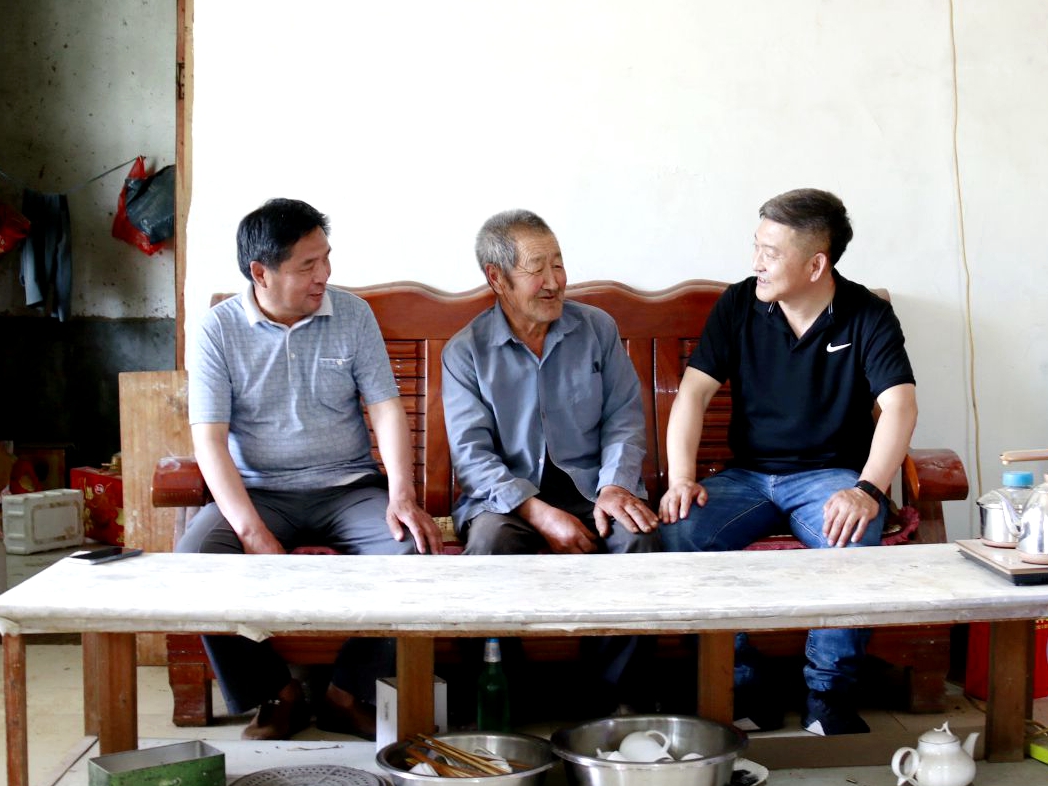 图为第一书记李国军（右一）和村干部入户收集村民发展特色农业的意见建议