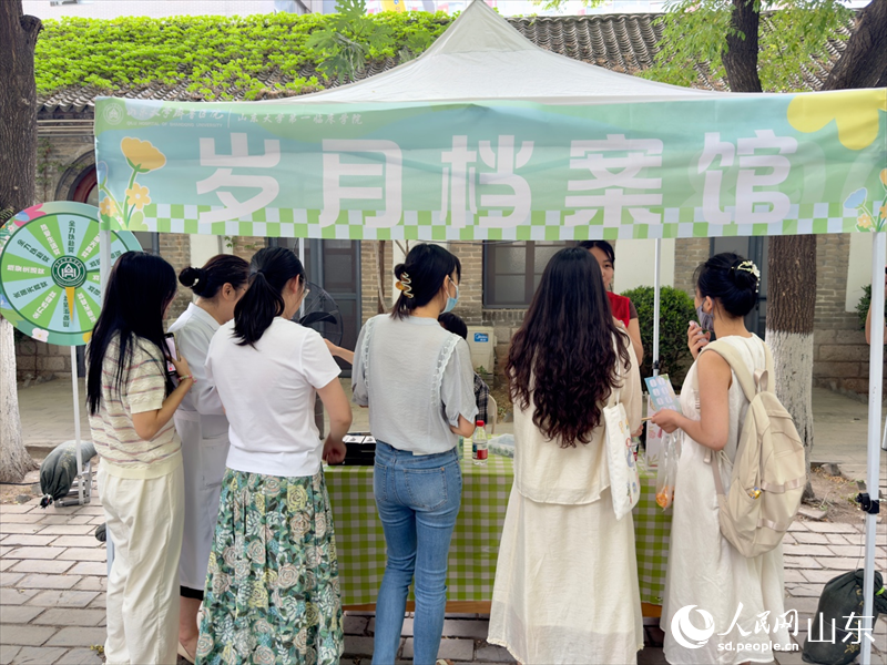 “岁月档案馆”摊位前，同学们踊跃答题。人民网 庄润泽摄