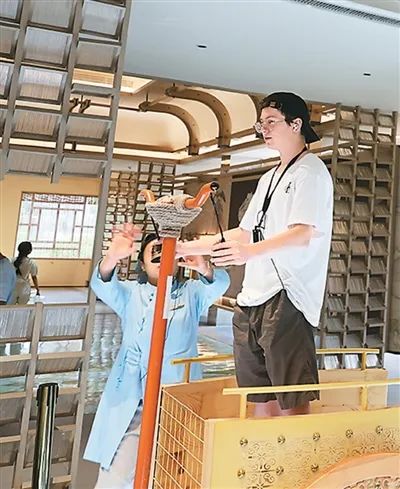 外国友人在尼山鲁源村“鸣和鸾”互动装置体验传统驾车技艺及礼仪。