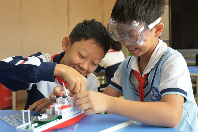 2025年9月25日，在山東省青島市市北區平安路第二小學開展的“校園科技之光”主題系列活動上，兩名學生在安裝科考船模型。
