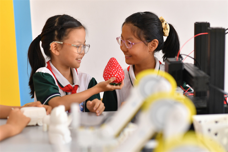 2025年9月25日，在山東省青島市市北區平安路第二小學開展的“校園科技之光”主題系列活動上，兩名學生在觀看3D打印的草莓。