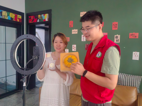 圖為丁麗（左）與客戶經理錄制月餅宣傳視頻