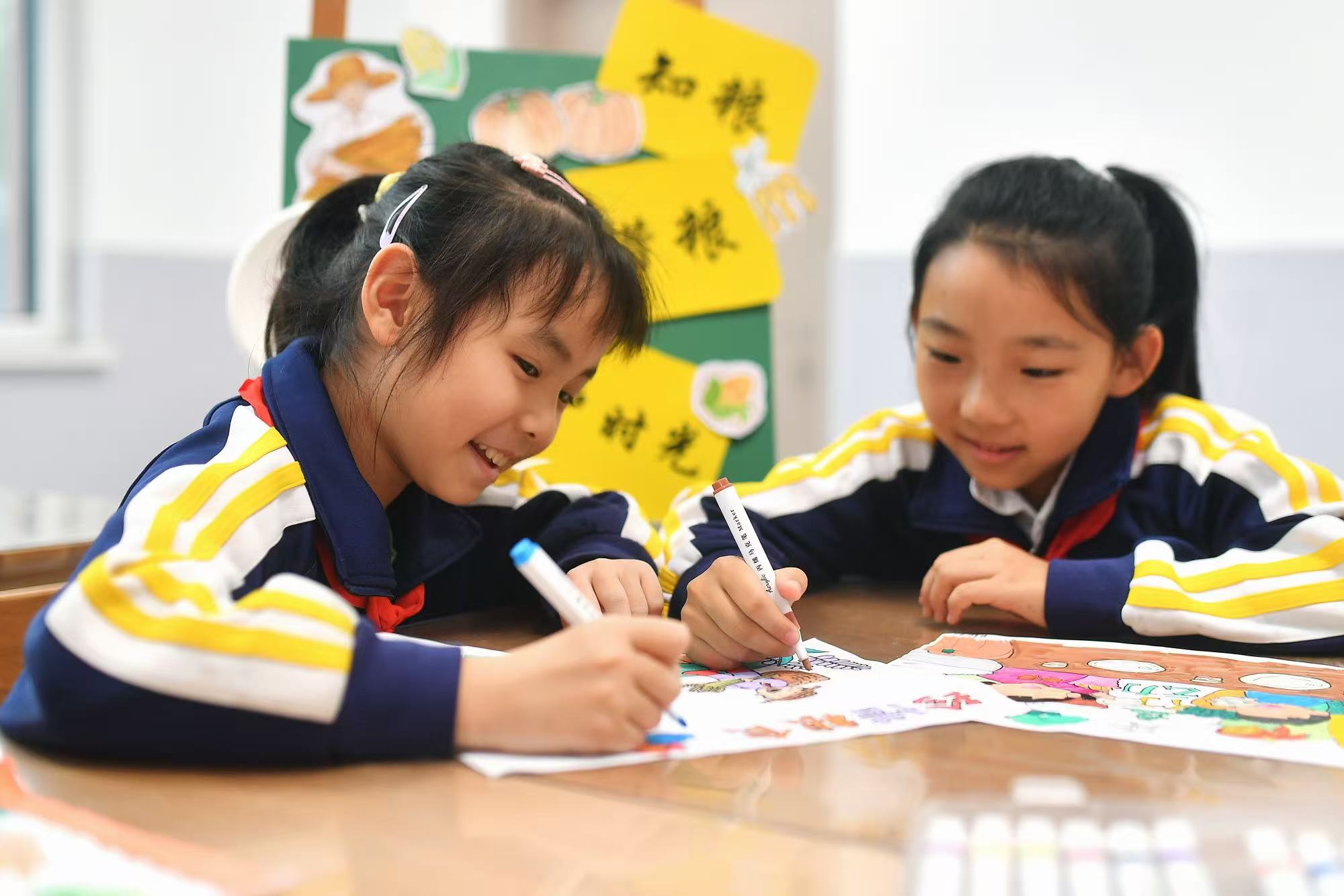 兩名學生在繪制珍惜糧食海報
