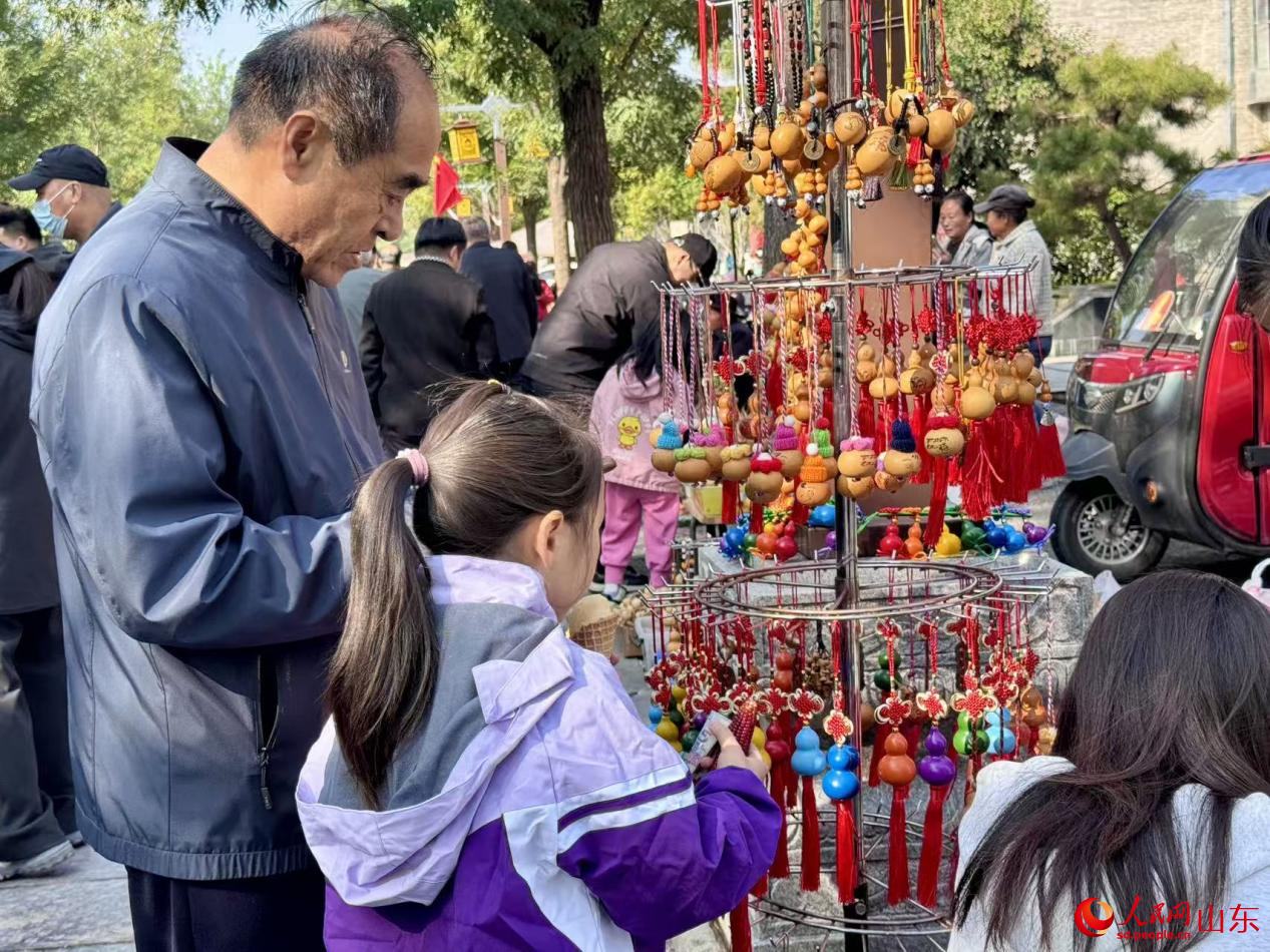 展位上葫芦工艺品琳琅满目,游客正驻足选购。人民网 郑昕桥摄