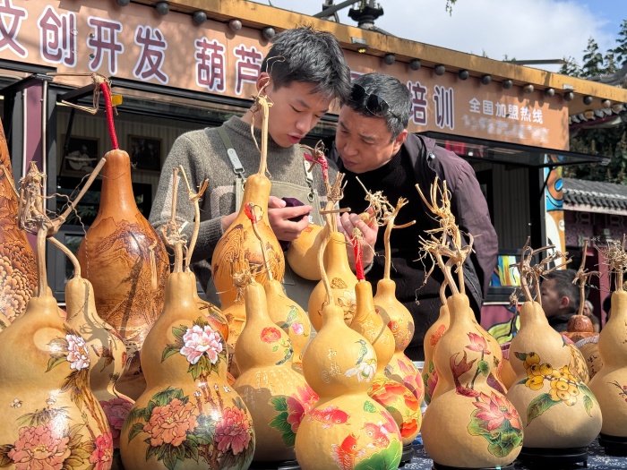 摊主正在讲解葫芦雕刻工艺。人民网 郑昕桥摄