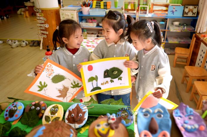 2025年10月23日，山东省青岛市市北区桦川路幼儿园的小朋友在讨论秋叶主题画作。