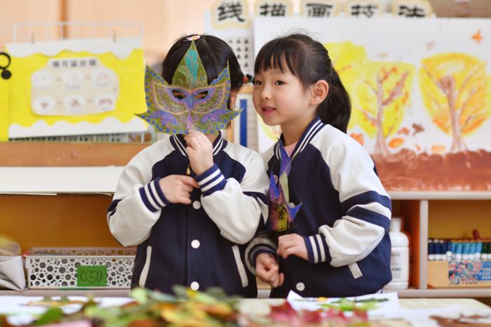 2025年10月23日，山东省青岛市市北区桦川路幼儿园的小朋友用秋叶画拍照。