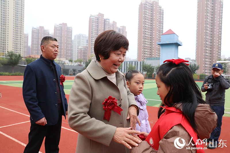 学生志愿者在签到台为老人佩戴胸花，老人脸上绽放出幸福灿烂的笑容。人民网记者 刘祺摄