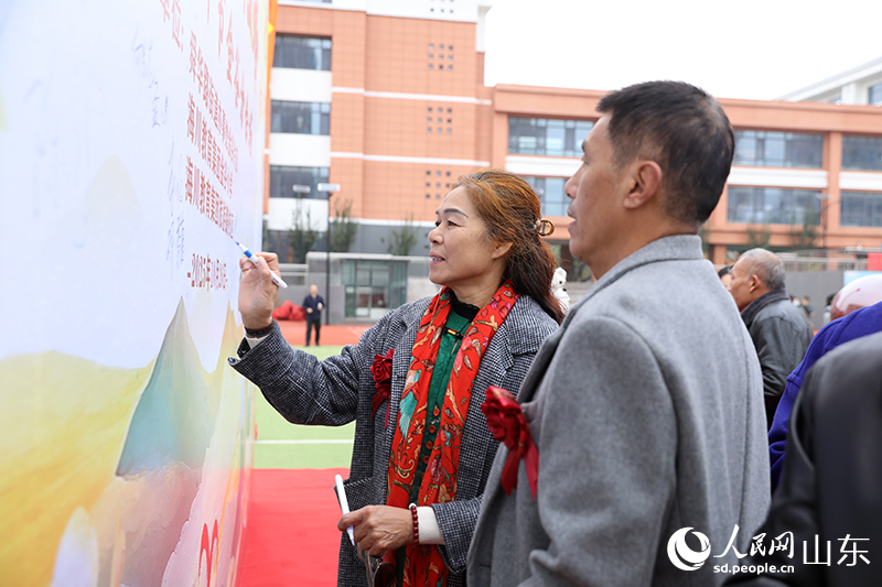 一对金婚夫妇在签名墙上郑重签下自己的名字，以跨越半个世纪的笔触，许下永恒的承诺。人民网记者 刘祺摄