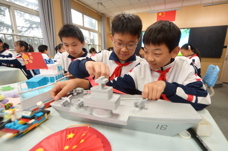 两名学生在整理利用废旧材料制作的航母模型。