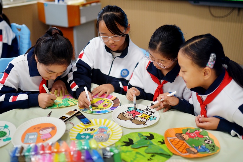 学生利用废旧物品制作纸盘画。