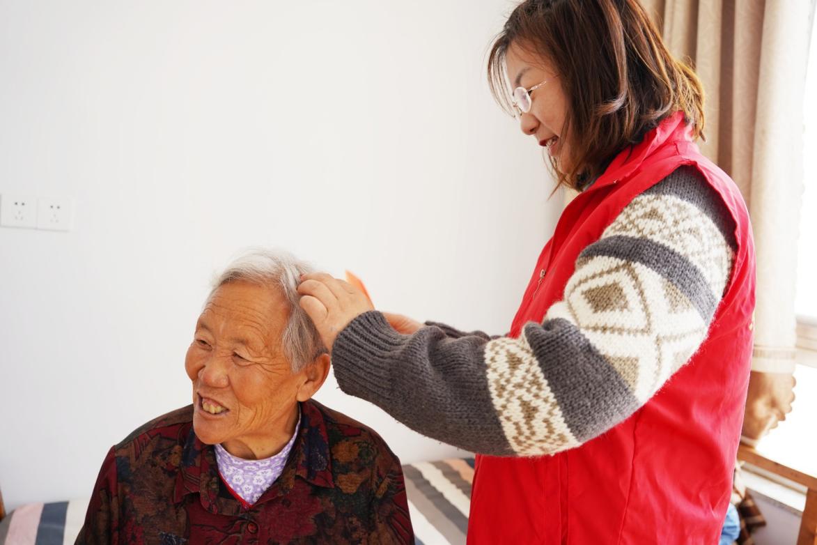 青年职工帮村民梳理头发,村民脸上洋溢着幸福的笑容