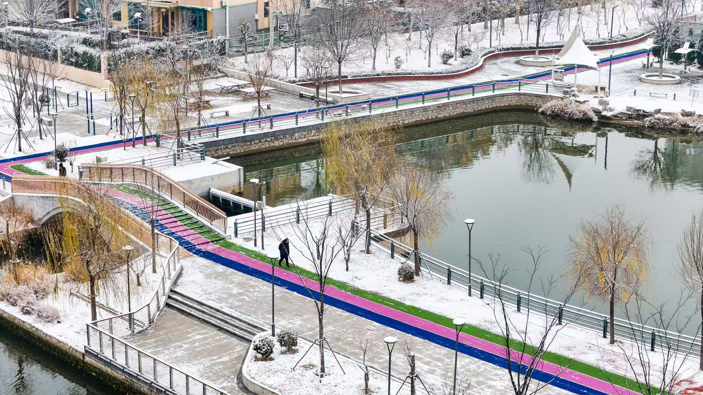 市民在山东省乐陵市玉心湖公园迎雪晨练