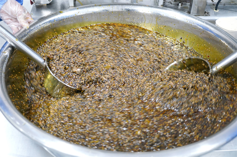 1月6日，在山东省临沂市沂南县岸堤镇泉水庄村“共富工坊”，村民将炒制的香椿酱搅拌均匀。