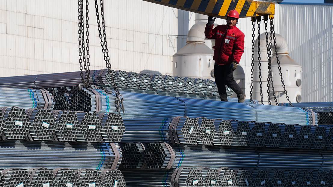 1月7日,位於山東省鄒平市焦橋鎮的山東君誠綠能材料科技有限公司工人在吊裝外運的鋼管。