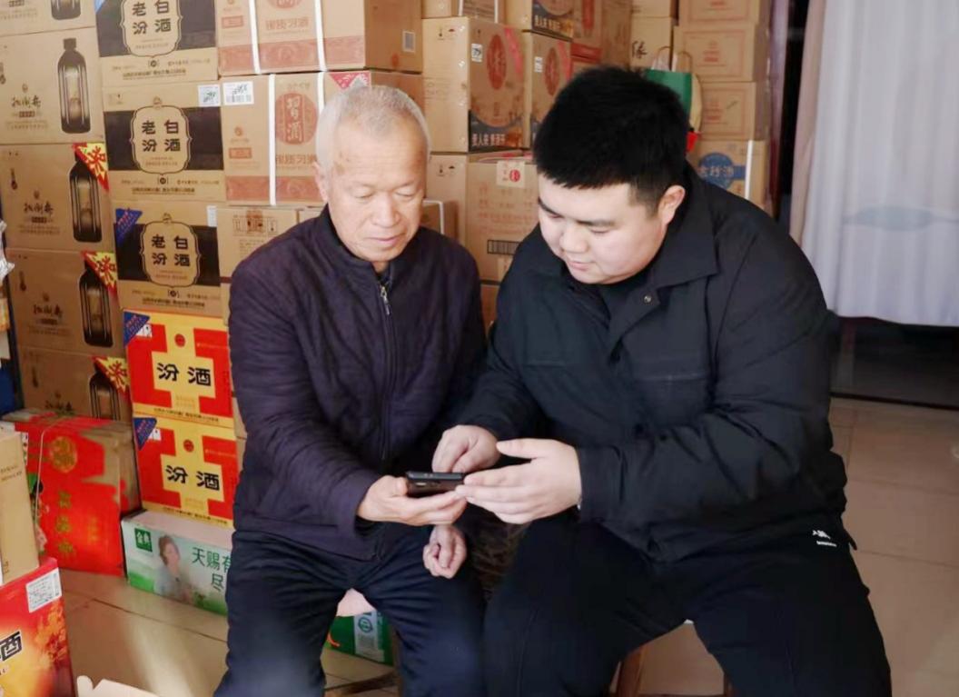 客戶經理李文鵬(左一)指導老年零售戶訂貨